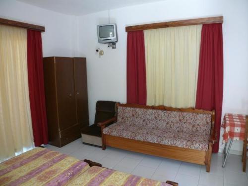 a bedroom with two beds and a couch and a tv at Senia Studios in Agia Marina Aegina