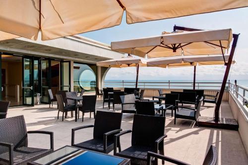 an outdoor patio with tables and chairs and umbrellas at Hotel Europa Beach Village in Giulianova