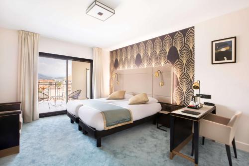 a hotel room with a bed and a desk and a window at Best Western Hôtel Journel Saint-Laurent-du-Var in Saint-Laurent-du-Var
