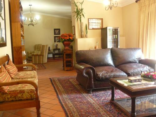 a living room with a leather couch and a table at Villa Jana Guesthouse in Pretoria