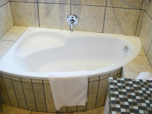 a bath tub with a faucet in a bathroom at Villa Jana Guesthouse in Pretoria