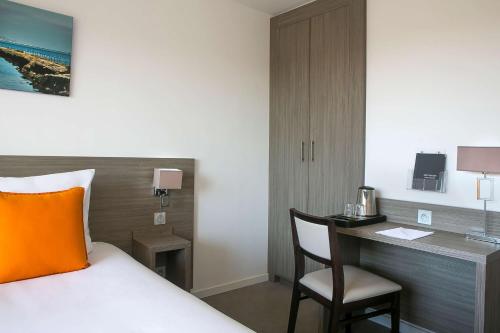 a bedroom with a bed and a desk with a chair at Best Western Hôtel des Thermes - Balaruc les Bains Sète in Balaruc-les-Bains