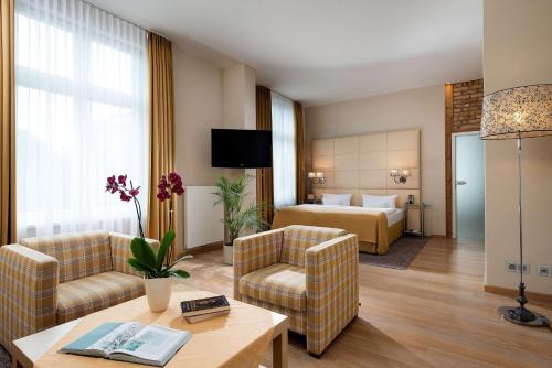 a hotel room with a bed and a living room at Best Western Plus Ostseehotel Waldschloesschen in Prerow