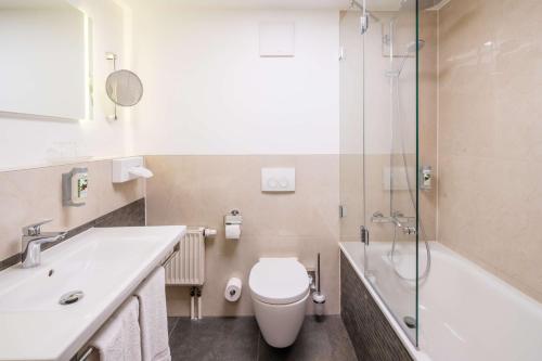 
a white toilet sitting next to a bath tub in a bathroom at Best Western Erfurt-Apfelstädt in Erfurt

