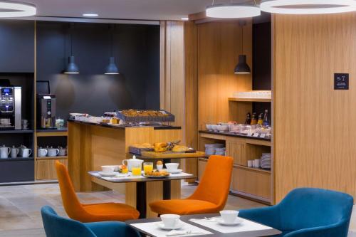 a restaurant with two tables and orange chairs and food at Best Western Plus Hotel Divona Cahors in Cahors
