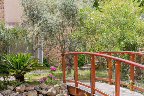 a wooden bridge over a garden with flowers and trees at Best Western Plus San Damianu in Sartène