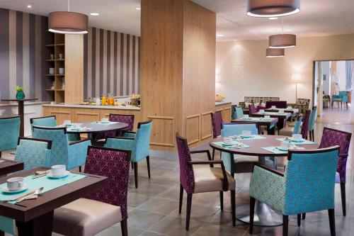 a restaurant with tables and chairs and a bar at Hôtel Le Rive Droite & SPA in Lourdes