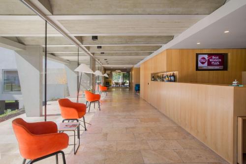 an office lobby with orange chairs and a counter at Best Western Plus Hotel Divona Cahors in Cahors