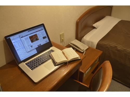 um computador portátil sentado numa secretária num quarto de hotel em Famy Inn Makuhari em Chiba