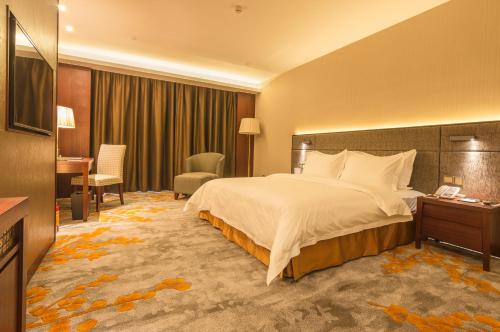 a hotel room with a large bed and a desk at The Summit Hotel in Zhongshan