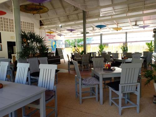 a dining room with white tables and white chairs at Diamond Sand Palace - SHA Plus in Ko Lanta