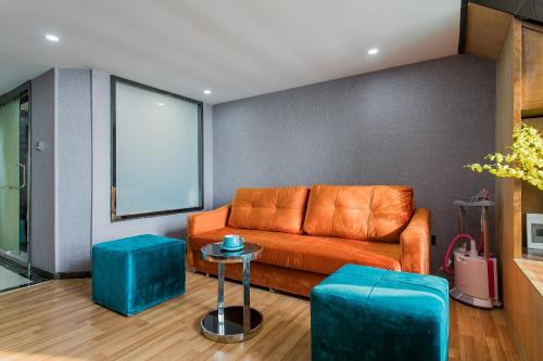 a living room with an orange couch and two blue stools at Lavendar Duplex Apartment in Guangzhou