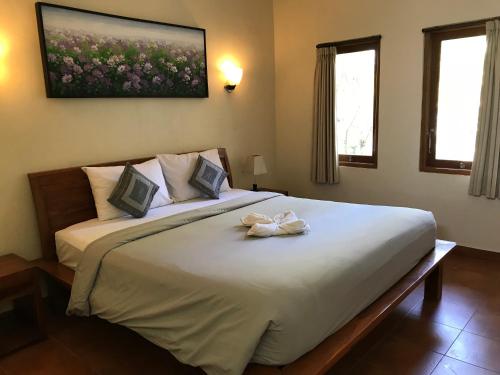 Un dormitorio con una gran cama blanca con dos flores. en Puri Clinton Bali, en Nusa Dua