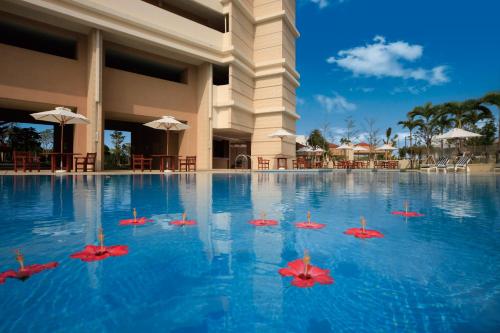 a pool at a resort with red umbrellas in the water at Moon Ocean Ginowan Hotel & Residence in Ginowan