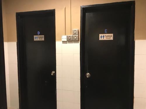two black doors in a bathroom with signs on them at Nusantara Mattwaddien Hostel in Kota Kinabalu