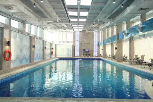 a large swimming pool with blue water in a building at Overseas Chinese Hotel Wenzhou in Wenzhou