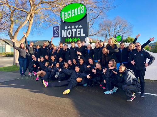 a group of people posing for a picture in front of a sign at Hacienda Motor Lodge in Palmerston North