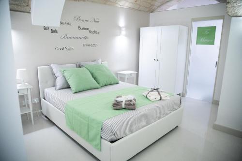 een witte slaapkamer met een groot wit bed met groene kussens bij Ta Maison Bari in Bari