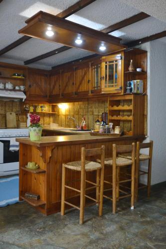 a kitchen with wooden cabinets and a counter with stools at House with Big Garden in Korinthos