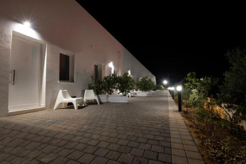 a row of white chairs on a sidewalk at night at Piano Monaco in Carini