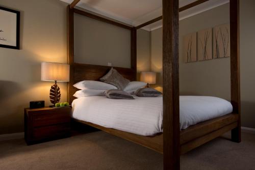 una camera con letto a baldacchino con lenzuola e cuscini bianchi di Crouchers Hotel a Chichester