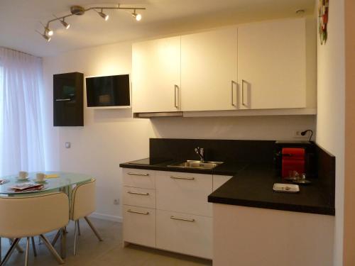 a kitchen with white cabinets and a small table at B&B "Clos Feuillat" in Lyon