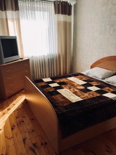 1 dormitorio con 1 cama con manta a cuadros en Welcoming apartment, en Anykščiai