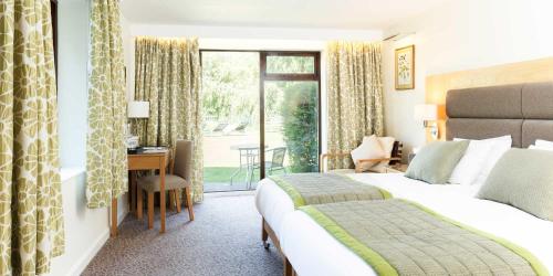 a hotel room with a bed and a desk and a window at Champneys Springs in Ashby de la Zouch