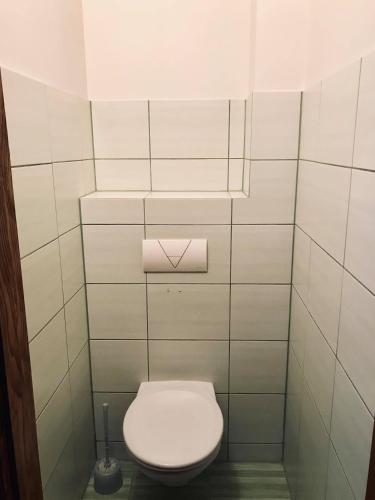 a bathroom with a toilet with a white tiled wall at Welcoming apartment in Anykščiai