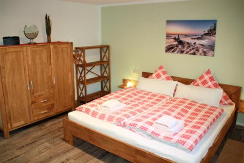 プレローにあるHeuser Prerow Ferienunterkünfteのベッドルーム1室(ベッド1台付)、木製キャビネットが備わります。