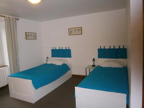 a bedroom with two beds with blue sheets at Les Sources in Saint-Jacques-des-Blats