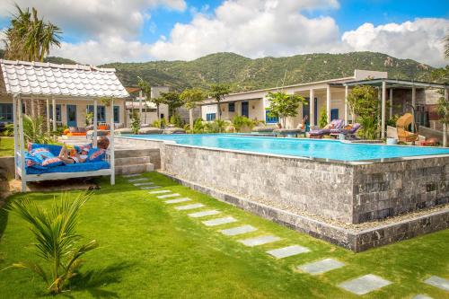 a swimming pool in a yard with people laying on chairs near a house at Sorrento Beach Club & Kite Village in Phan Rang
