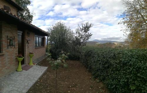 une cour avec une maison, une haie et un bâtiment dans l'établissement Il Castagneto, à Camerino