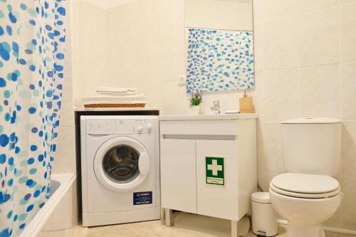 a bathroom with a washing machine and a toilet at Peaceful & Spacious Apt with Parking & Queen Bed in Carvoeiro