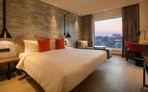 a bedroom with a large bed and a large window at Lemon Tree Premier City Center Pune in Pune