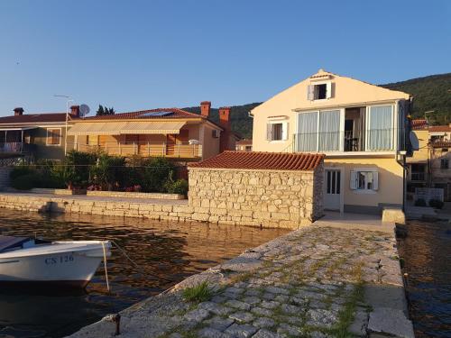 ein Haus und ein Boot in einem Wasserkörper in der Unterkunft Cres view apartments in Cres