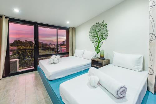 twee bedden in een kamer met een raam bij Eco Hostel in Phuket