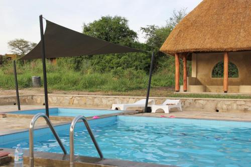 a swimming pool with an umbrella and a gazebo at Fort Murchison Lodge by NATURE LODGES LTD in Pakwach East