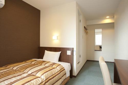 a hotel room with a bed and a table at Hotel Kudou Oita in Oita