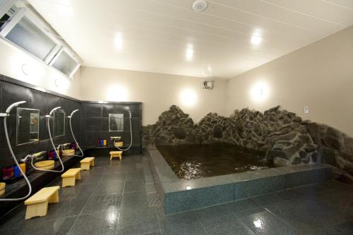 a bathroom with a large tub with a rock wall at Hotel Kudou Oita in Oita