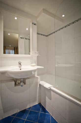a white bathroom with a sink and a tub at Austin's Arts Et Metiers Hotel in Paris