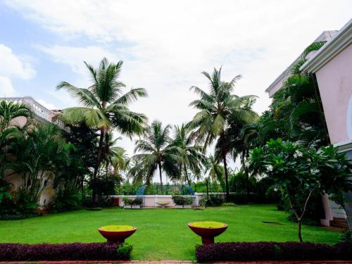 a garden with palm trees and a lawn at Club Mahindra Emerald Palms, Goa in Varca