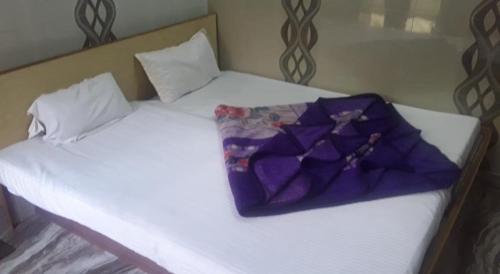 a white bed with a purple blanket on it at Hotel Ashoka in Ajmer