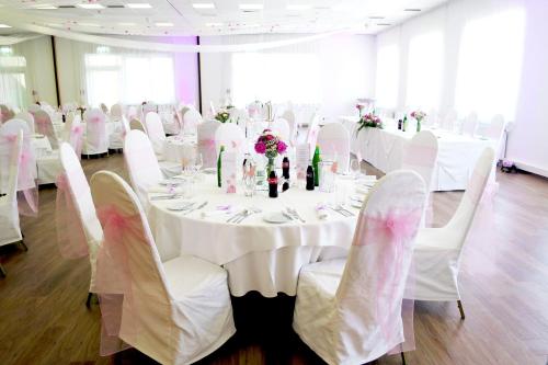 a room with white tables and chairs with white tablecloths at NOVAPARK Flugzeughotel Graz in Graz