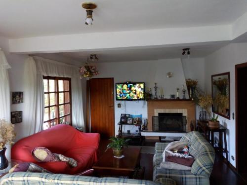sala de estar con silla roja y sofá en Casa Flor de Liz, en Campos do Jordão