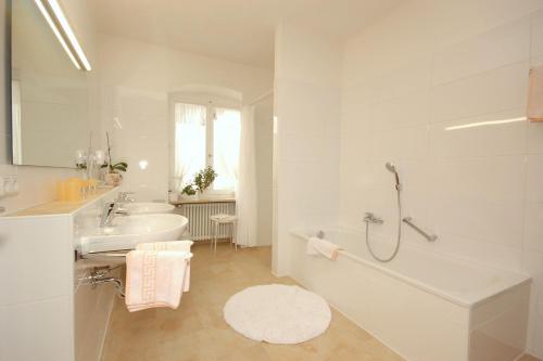 a white bathroom with a tub and a sink at Hotel Hirschen in Sankt Peter