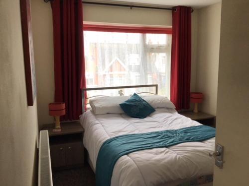 1 dormitorio con 1 cama y una ventana con cortinas rojas en 9 Gunfleet court en Clacton-on-Sea