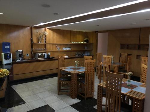 a restaurant with wooden tables and chairs and a counter at Horto Executivo Hotel in Ipatinga