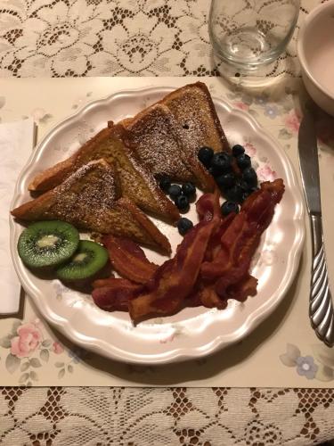 a plate of toast and bacon and fruit on a table at Carriage Stop Bed & Breakfast in Palmyra