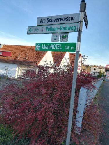 a street sign with several street signs on a pole at mein kleinHOTEL in Herbstein